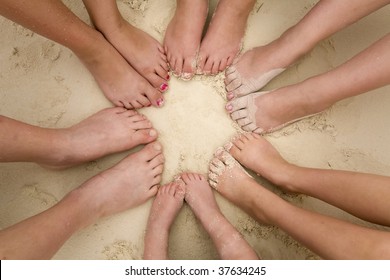 A Bunch Of Kids Feet Laying In A Circle In The Sand.
