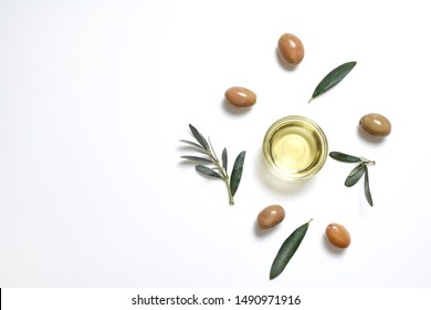 Bunch of local produce Turkish green gemlik olives with glass cup of extra virgin golden oil and olea europaea tree leaves. Close up, top view, copy space, isolated white background. - Shutterstock ID 1490971916