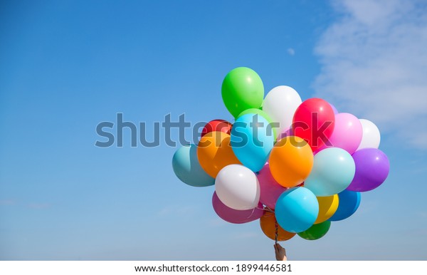 A bunch of multicolored balloons with helium\
on a blue sky background