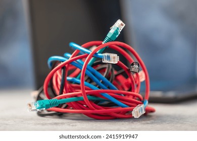 A bunch of network computer wires tangled together on the background of a laptop, a concept on the topic of difficulty when connecting to a local network or the Internet via a wire