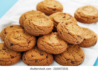 A bunch of oatmeal cookies with chocolate on a napkin on a blue background. Top view, free space - Powered by Shutterstock