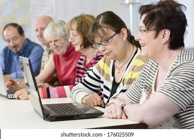 A Bunch Of Older People Looking At Computers In A Classroom.