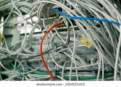 a bunch of patch network cables sorted in a rack cabinet leading from a patch panel in a server rack in data center room internet cloud storage
