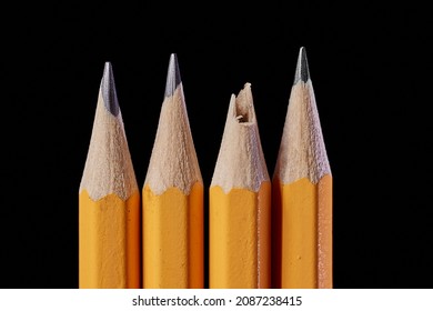 A bunch of pencils one with broken missing tip isolated on black background