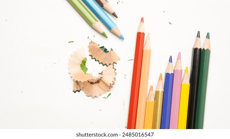 A bunch of pencils with a pile of pencil shavings on a white background. The pencils are of different colors and sizes - Powered by Shutterstock