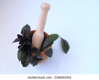 A Bunch Of Purple Basil In A Wooden Mortar For Grinding Spices. Wooden Pestle. View From Above. Isolated On White Background.