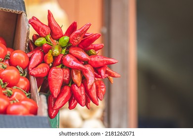 Bunch of red hot chili peppers hanging in a street food market, close up