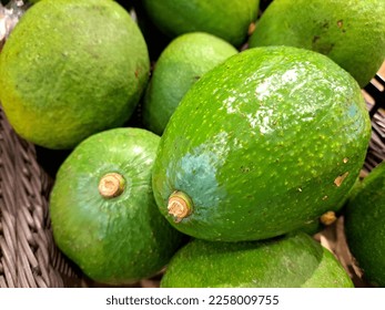 A bunch of ripe avocados with green skin on the supermarket shelf and ready to be sold - Shutterstock ID 2258009755