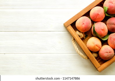 Bunch Of Ripe Organic Peaches In Pile On Wooden Tray Tray With Rope Handles On White Wood Textured Table. Local Produce Harvest Heap. Clean Eating Concept. Background, Top View, Close Up, Copy Space.