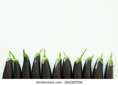 Bunch of ripe organic polished eggplants laid in composition on white background. Harvest heap of aubergine vegetables at table counter. Clean eating concept. Background, close up, flat lay, top view.
