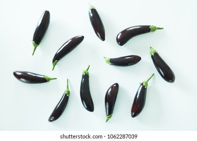 Bunch of ripe organic polished eggplants laid in composition on white background. Harvest heap of aubergine vegetables at table counter. Clean eating concept. Background, close up, flat lay, top view.