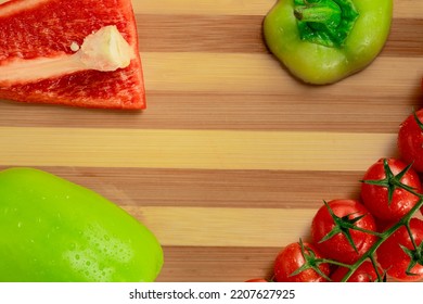 A Bunch Of Ripe Red Cherry Tomatoes And Chopped Pieces Of Green Sweet Pepper On A Striped Wooden Board. Top View Of Tomatoes And Sweet Peppers Wet From Moisture Drops. Fresh Vegetables. Close Up.