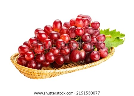 Bunch of ripe red grapes, Crimson Seedless Grapes,  with green leaf in bamboo tray isolated on white background with clipping path.