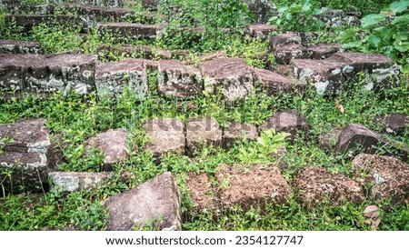A bunch of rocks sitting on top of a lush green field, ancient ruins in the forest, ancient overgrown ruins, ancient temple ruins. 