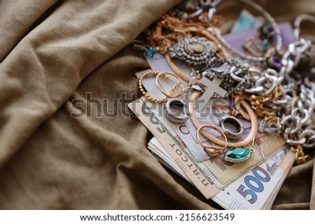 Bunch of stolen jewelry and money on military uniform cloth fabric. Looting by Russian soldiers in the Ukrainian cities during the Russian attack on Ukraine. Marauders and looters concept Foto stock © 