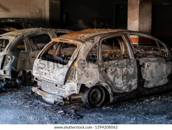 A bunch of totally burnt out cars or\
vehicles wreckage in an underground parking garage. Total damage,\
insurance case, fire protection\
concept.