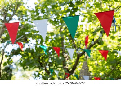 A bunch of triangle flags hanging from a tree. garland flags among for outdoor party.
