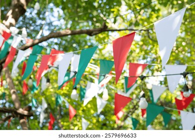 A bunch of triangle flags hanging from a tree. garland flags among for outdoor party.