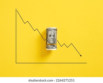 Bunch of United States dollar money with a decreasing graph on yellow background. Dollar currency fluctuation, inflation and stock market value loss.
