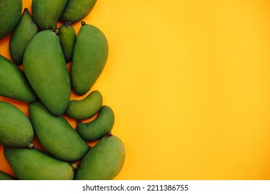 Bunch of unripe mangoes with bright orange paper background