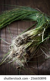 Bunch Of Wild Chives With Roots On Wooden Table With Natural Sunbeam