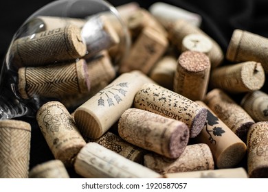 Bunch of wine corks, empty wine bottle and a glass over a black blanket
