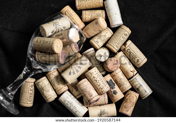 Bunch of wine corks, empty wine bottle and a\
glass over a black\
blanket\
