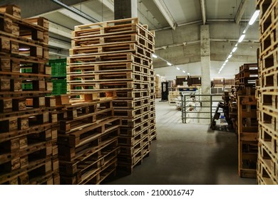 Bunch Of Wooden Pallets In The Warehouse. Empty Warehouse Space With Lots Of Pallets Neatly Stacked In The Factory Plant. Indoor Warehouse With No People, Distribution And Logistics, Supply