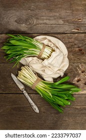 Bunches of a fresh harvest of spring ramson or wild leek. Fragrant spicy leaves on vintage wooden table background, hard light, dark shadow, top view