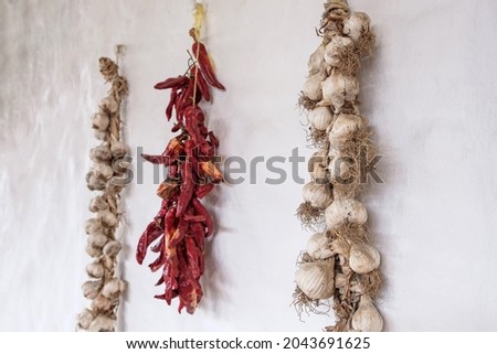bunches of peppers and garlic hanging on the wall. storing garlic and peppers in the old traditional way