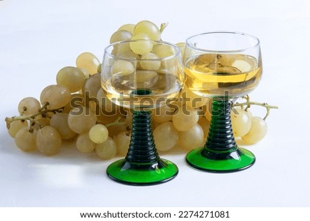 Bunches of white grapes and Alsace wine glasses on white background