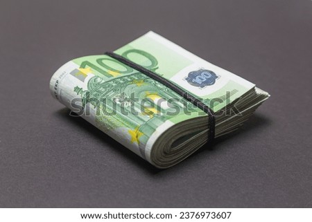 A bundle of 100 EURO banknotes folded in half on a dark background.
