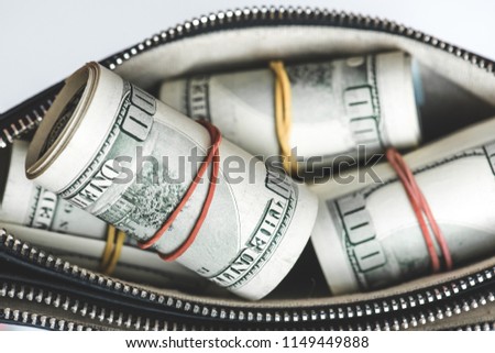 A bundle of 100 US dollar bills in a purse