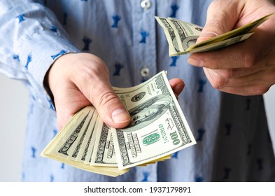 A bundle of American dollars money is rolled up in a hand. Money tied with an elastic band. Roll of American dollars. Human hand. Business and finance. Currency and finance. Cash business.