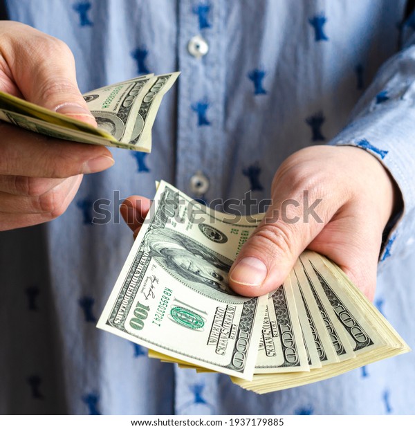 A bundle of American dollars money is rolled up\
in a hand. Money tied with an elastic band. Roll of American\
dollars. Human hand. Business and finance. Currency and finance.\
Cash business.