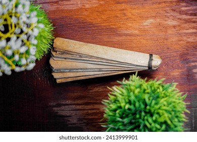 Bundle of ancient palm leaves dried palm leaf for manuscripts on hand in wooden background, its used as writing material in ancient times, blank dried palm leaf with text space. top view,side view.