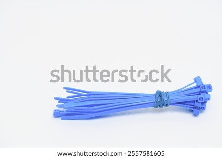Bundle of Cable Ties. Close-up of a bundle of red plastic cable ties secured with a blue string, isolated on a white background for organization and utility.	
