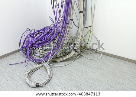 A bundle of communication cables are hanging from the ceiling in room.