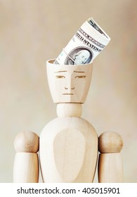 Bundle of dollars into the human head. Abstract image with wooden puppet