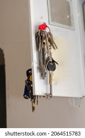 A bundle of door keys hangs from a small metal door. Random keys to front doors and rooms. Close-up. Inside the room. Selective focus.
