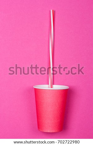 a bundle of multi-colored drinking straws in a paper Cup on a pink background. fashion minimal. flat lay