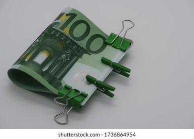 A Bundle Of One Hundred Euro Banknotes With Large And Small Green Paper Clips, A Tight Grip