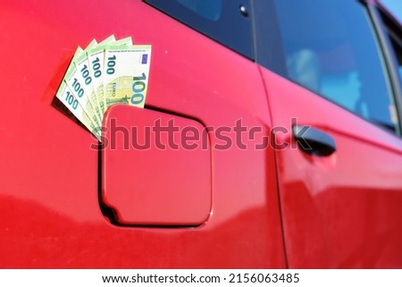 A bundle of one hundred euro banknotes in the fuel tank cap of a car  Symbol for the rising fuel price 