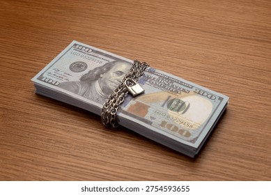 A bundle of one hundred US dollar bills bound with a metal chain and secured with a padlock. Financial security, asset protection, frozen accounts, and investment safety concept.
