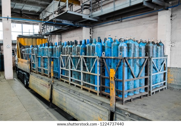 A bundle of oxygen cylinders with\
compressed gas secured on yellow skids in platform. Blue Oxygen\
tanks for industry. Liquefied oxygen production.\
Factory