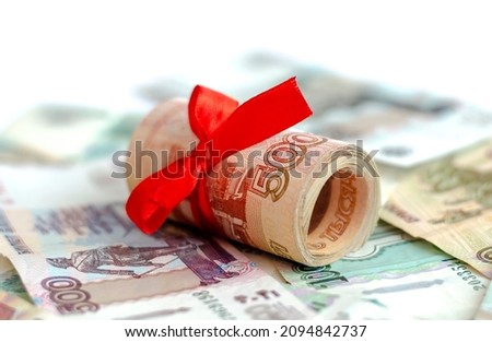 A bundle of Russian money tied with a red satin ribbon with a face value of 5000 rubles, lying on Russian banknotes. The concept of finance, investment, savings and cash.