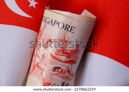 Bundle of Singapore dollars with the flag as background.