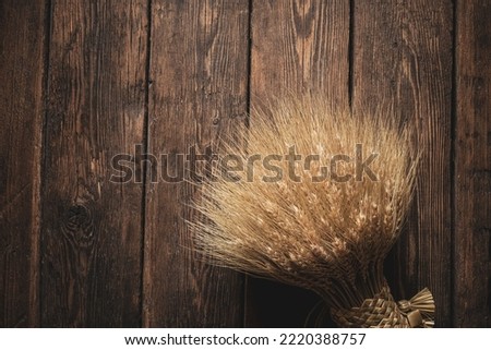 The bundle of wheat ears on a dark timber-aged wooden table surface. Wheat sheaf with copy space.