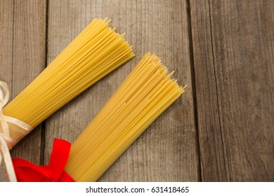 Bundles of raw spaghetti tied with ribbons on wooden surface - Powered by Shutterstock