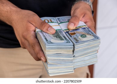 Bundles of US dollars in the hands of businessman. Selective focus - Shutterstock ID 2207802509